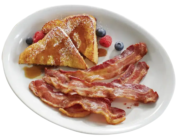 Plate with french toasts, berries and bacon strips